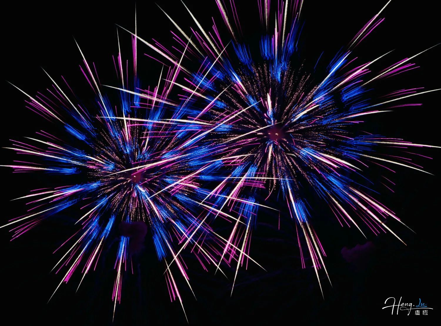 Blue-and-pink-fireworks-burst-vividly-in-night-sky