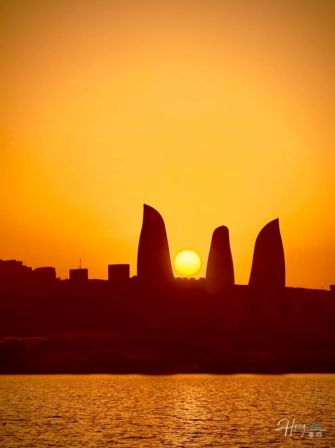 Sunset-over-modern-city-silhouette-by-water