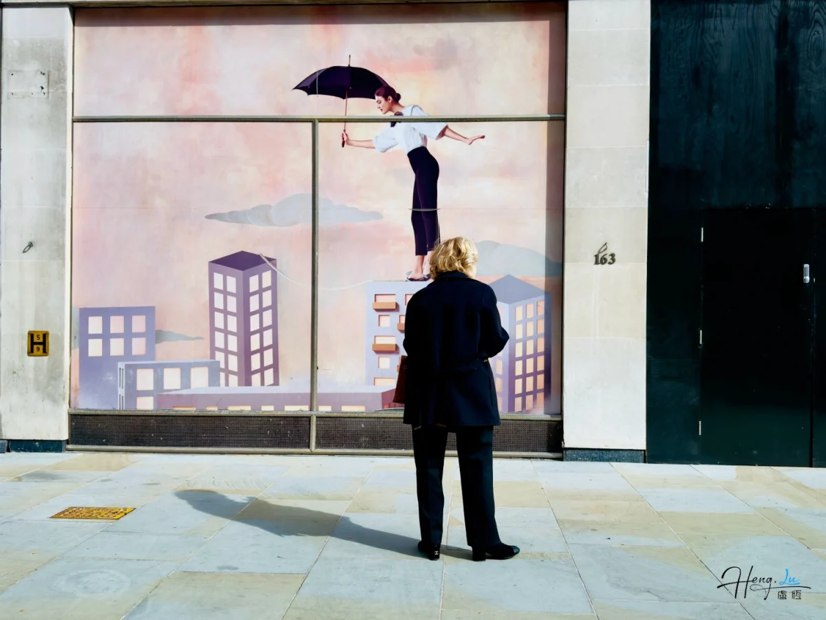 Woman viewing whimsical mural of figure balancing above city