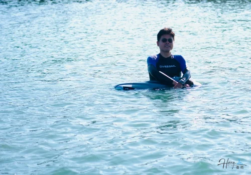 luheng-in-wetsuit-sitting-on-paddleboard-in-water