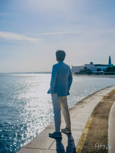 luheng-standing-by-seaside-gazing-at-sunlit-water