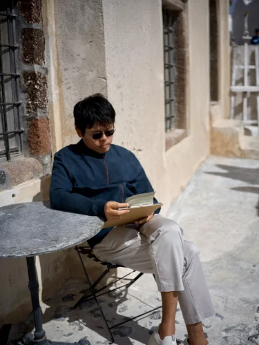 portrait-of-luheng-reading-outdoors-by-stone-wall-under-sunlight
